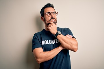 Handsome man with beard wearing t-shirt with volunteer message over white background Thinking worried about a question, concerned and nervous with hand on chin