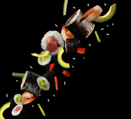 Delicious sushi rolls and ingredients on black background