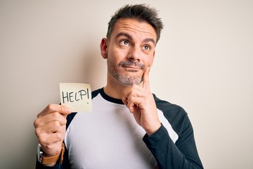 Young handsome man stressed holding reminder paper with help message serious face thinking about...
