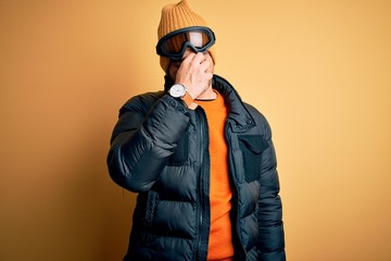 Young handsome skier man skiing wearing snow sportswear using ski goggles tired rubbing nose and eyes feeling fatigue and headache. Stress and frustration concept.