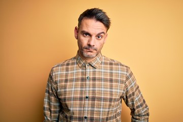 Young handsome man wearing casual shirt standing over isolated yellow background skeptic and nervous, frowning upset because of problem. Negative person.