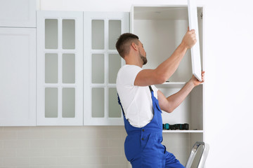Fototapeta na wymiar Worker installing door of cabinet in kitchen