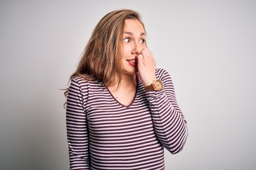 Young beautiful blonde woman wearing casual striped t-shirt over isolated white background looking stressed and nervous with hands on mouth biting nails. Anxiety problem.