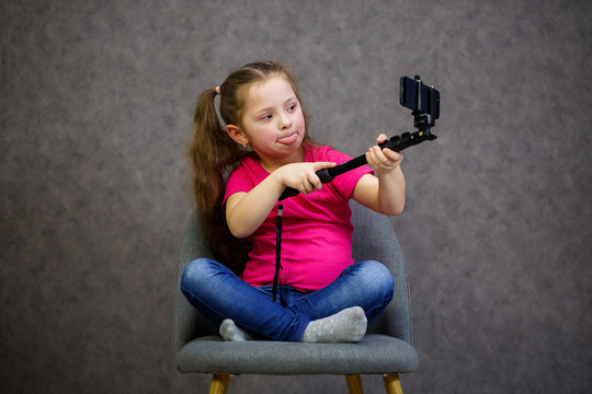 Girl in A T-shirt takes a selfie on her phone and poses