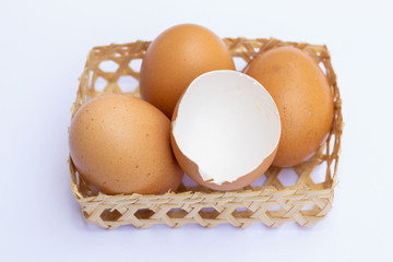 Brown chicken eggs are placed in bamboo trays. With an eggshell on a white background