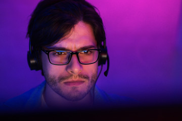 Millennial Guy Playing Online Videogame Sitting At Home, Neon Lights