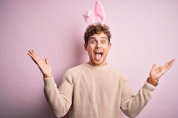 Young handsome blond man wearing easter rabbit ears over isolated pink background celebrating crazy...