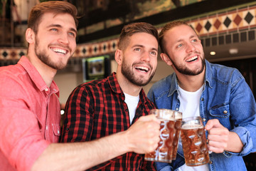 Watching football in bar. Happy friends drinking beer and cheering for favorite team, celebrating victory.