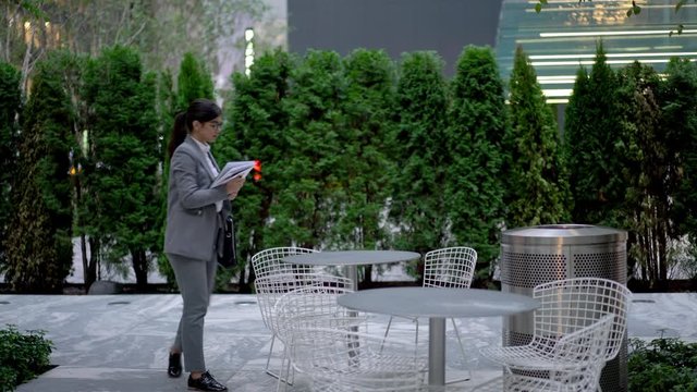 Attractive female trader with leather briefcase sitting in street cafe for analyzing information during distance work with financial startup project, intelligent proud coe using touch pad