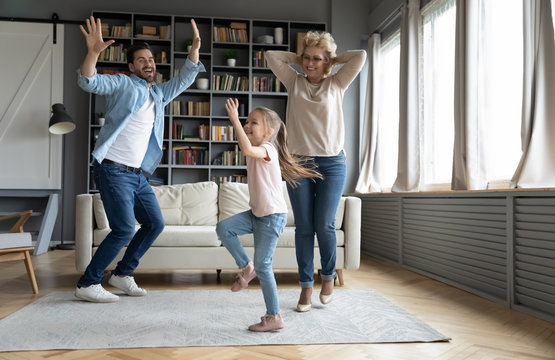 Overjoyed three family generations dancing at home