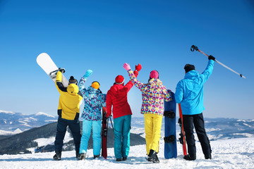 Group of friends with equipment at ski resort, back view. Winter vacation