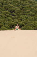 young shipwrecked man sitting on top of a sand dune