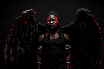 gorgeous and fantastic dark angel having big black wings, african male with strong body stand in...