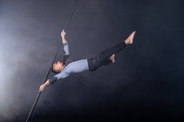 Performance concept. Man hanging on chinese pole. Athlete performing flying pole