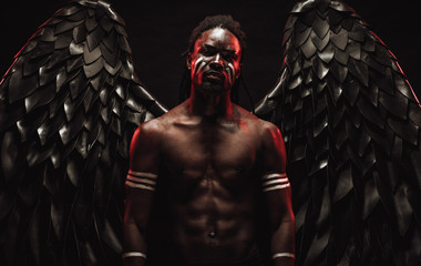 strong muscular angel with black wings fall on the earth, extraordinary african man stand in the flesh of dark angel and illustrated dark forces. isolated photoshoot