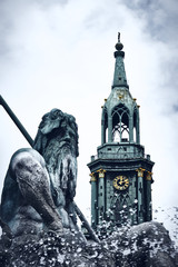 Neptune on fountain with church tower in the background. Desaturated colors and overexposed sky.