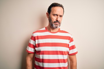 Fototapeta premium Middle age hoary man wearing casual striped t-shirt standing over isolated white background skeptic and nervous, frowning upset because of problem. Negative person.