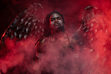 portrait of reckless dark angel with strong muscles, having athletic body, african man in the flesh...