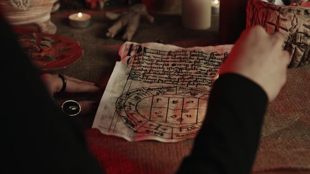 Partial view of witch dripping wax on pentagram during occult ritual