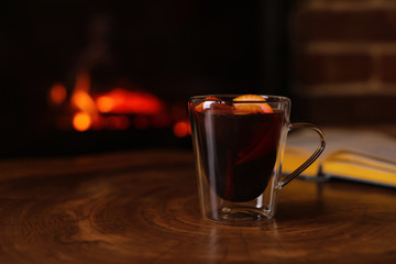 Tasty mulled wine and blurred fireplace on background