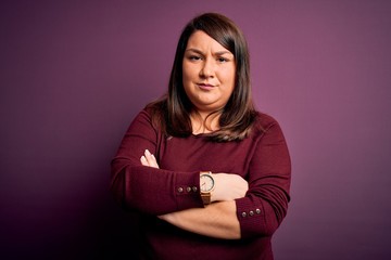 Obraz premium Beautiful brunette plus size woman wearing casual sweater over isolated purple background skeptic and nervous, disapproving expression on face with crossed arms. Negative person.