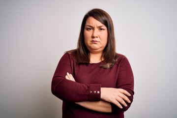 Beautiful brunette plus size woman wearing casual sweater over isolated white background skeptic and nervous, disapproving expression on face with crossed arms. Negative person.