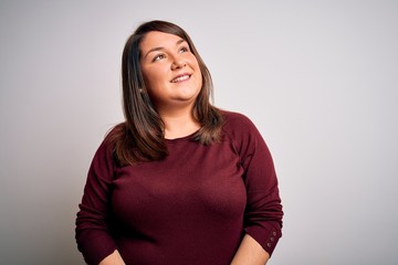 Beautiful brunette plus size woman wearing casual sweater over isolated white background looking away to side with smile on face, natural expression. Laughing confident.