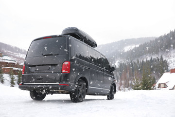 Black car on snowy road. Winter vacation