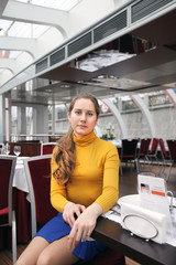 Girl in bright clothes in a cafe with a glass ceiling