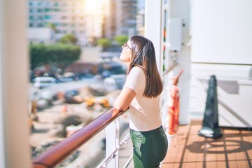 Young beautiful woman on vacation smiling happy and confident. Standing on a deck of ship with smile on face doing a cruise