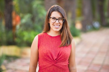 Young beautiful girl smiling happy and confident walking at the town park, standing with a smile on face