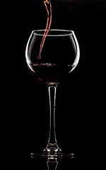 Silhouette of a glass on a black background, a red drink is poured on top