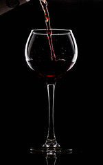 Silhouette of a glass on a black background, a red drink is poured on top