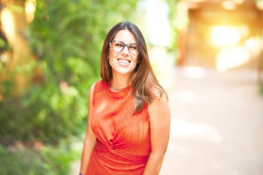 Young beautiful girl smiling happy and confident walking at the town park, standing with a smile on face