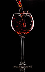 Silhouette of a glass on a black background, a red drink is poured on top
