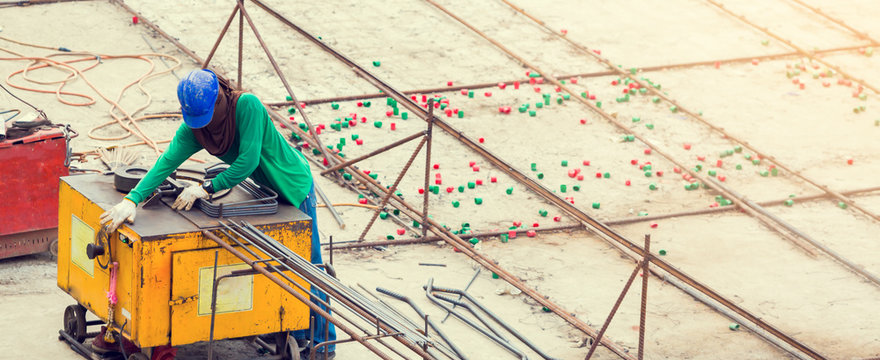 Construction worker and many deformed steel bar working with electric iron bending machine at the construction site.
