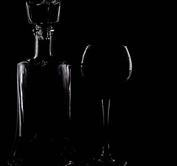 Silhouette of a glass and decanter on a black background, with a red drink inside