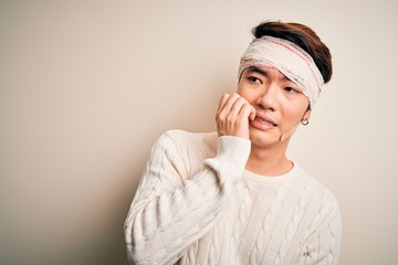 Young handsome chinese man injured for accident wearing bandage and strips on head looking stressed and nervous with hands on mouth biting nails. Anxiety problem.