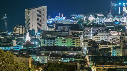 Cityscape of Monte Carlo, Monaco night timelapse with roofs of buildings and traffic on roads.