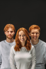 positive beautiful caucasian red haired people together isolated over black background . brothers and sister having red unusual hair posing at camera and smile. emotions, queerness, people concept