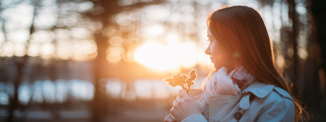 Portrait of a girl with willow branches in early spring at sunset.