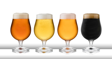 Four glasses of refreshing lager, beer, cider and stout, in  schooner glasses, with condensation, on a white table and white background