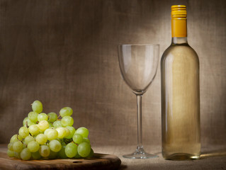 Obraz premium White grapes and bottle and glass of wine. Still life, wine making, Hessian background.