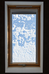 roof window with snow on a winter day. sunlight through the attic window, light in the house, skylights. vertical image