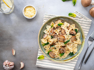farfalle pasta with mushrooms and spinach, served in a ceramic plate. Gray background. horizontal image. top view. copy space
