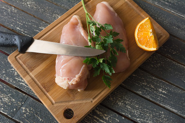 Fresh chicken and parsley on a wooden kitchen board.