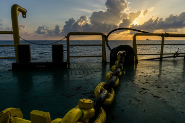 Towing chain of a construction work barge at oil field during sunset
