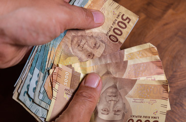 Male hand hold a fan Indonesia rupiah banknote, the currency of Indonesia. Close up to the dirty...