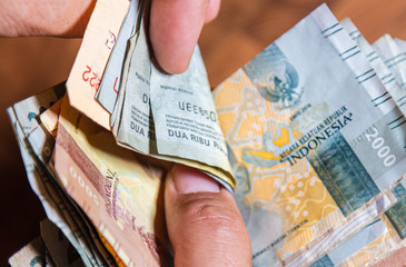 Male hand hold a fan Indonesia rupiah banknote, the currency of Indonesia. Close up to the dirty...