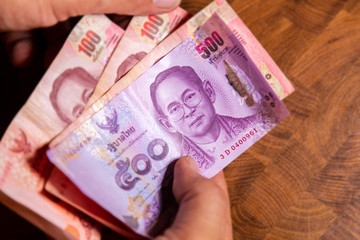 Male hand show thai baht banknote, the official currency of Thailand. On front the portrait of the Rama or King,  Close up Paper Money of Thailand. 10th most frequently used world payment currency